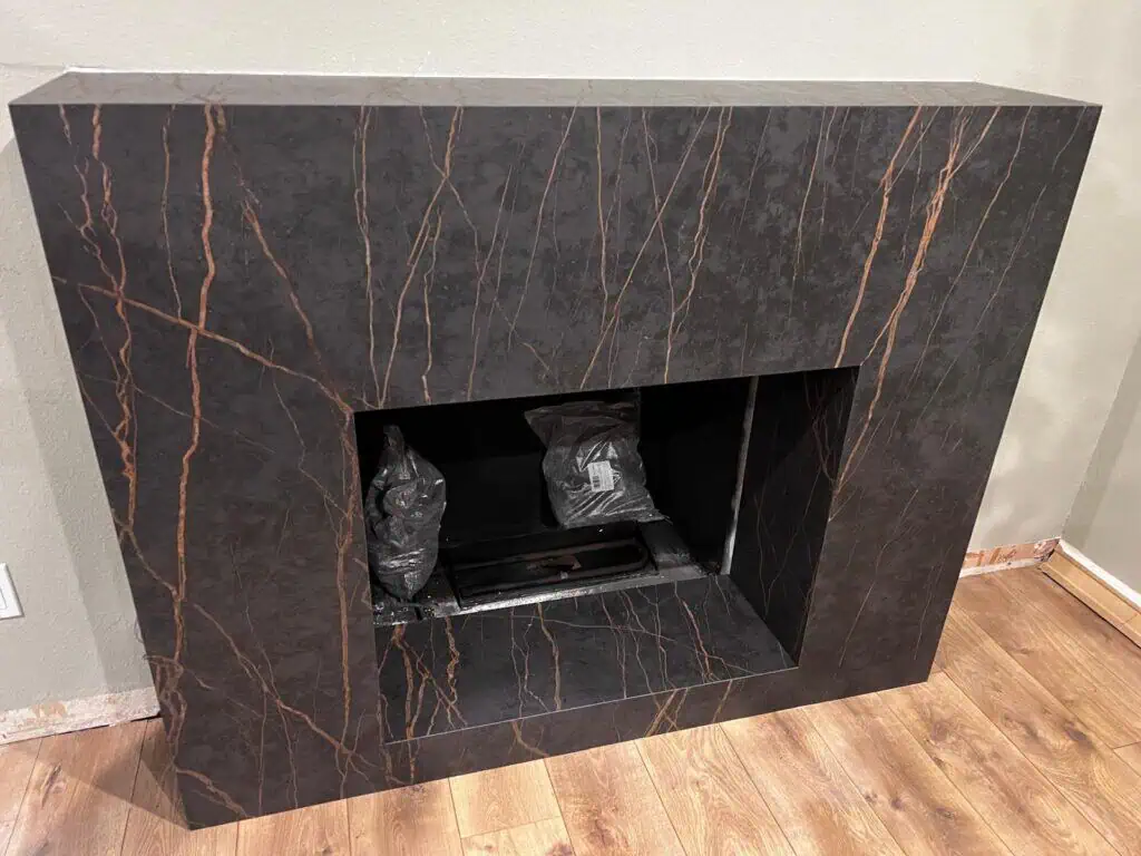 Modern black marble fireplace with copper veining in a living room setting.