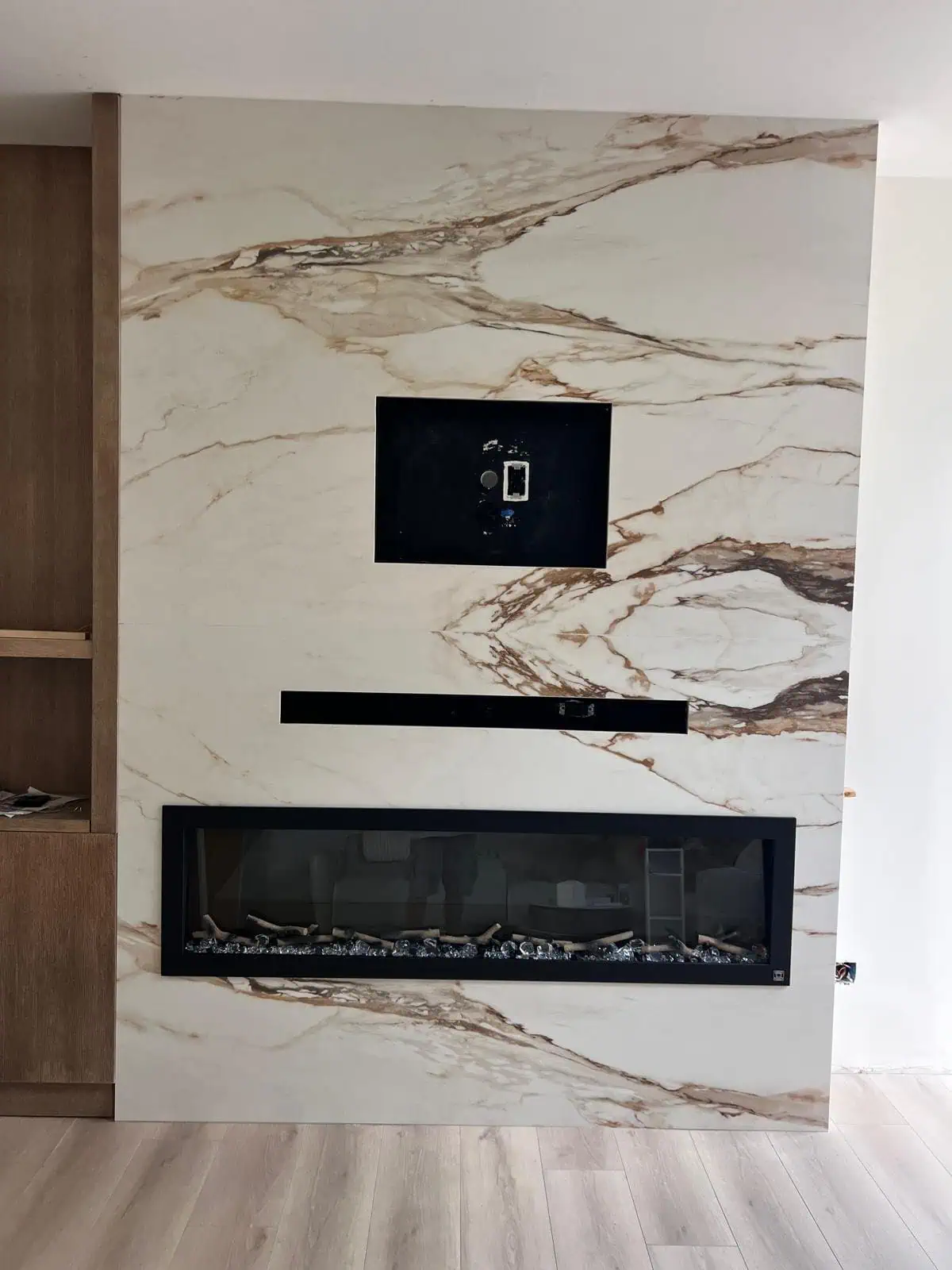 A modern marble fireplace with built-in TV and sleek black accents.