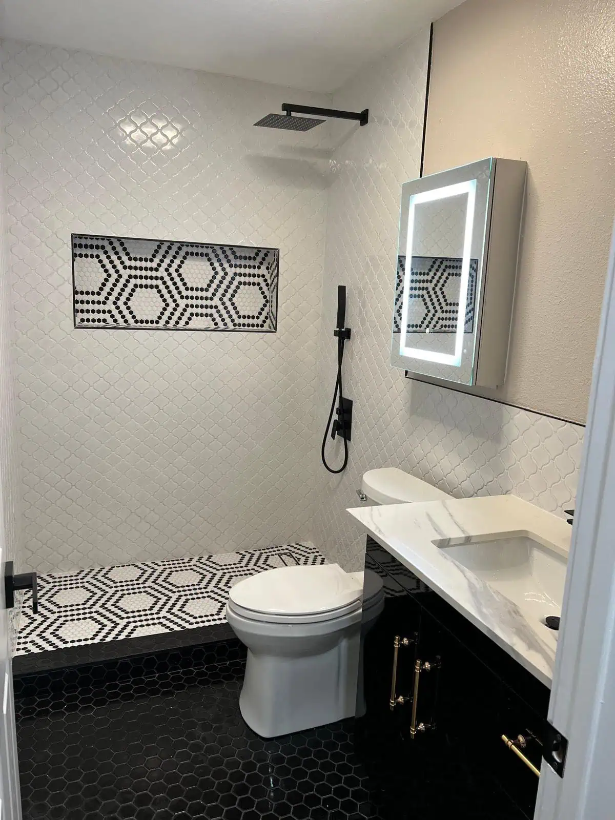 Modern bathroom with walk-in shower, black and white tile design, and sleek vanity.