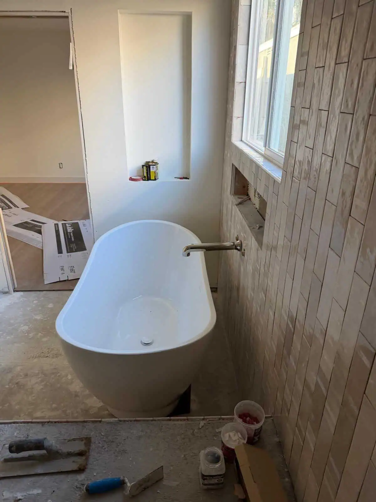 Modern bathroom renovation with freestanding bathtub and stylish wall tiles.