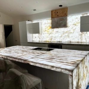 Onyx marble kitchen island with modern cabinetry and backsplash, under construction or renovation.