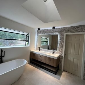Modern bathroom with skylight, double vanity, and freestanding tub in a contemporary home.